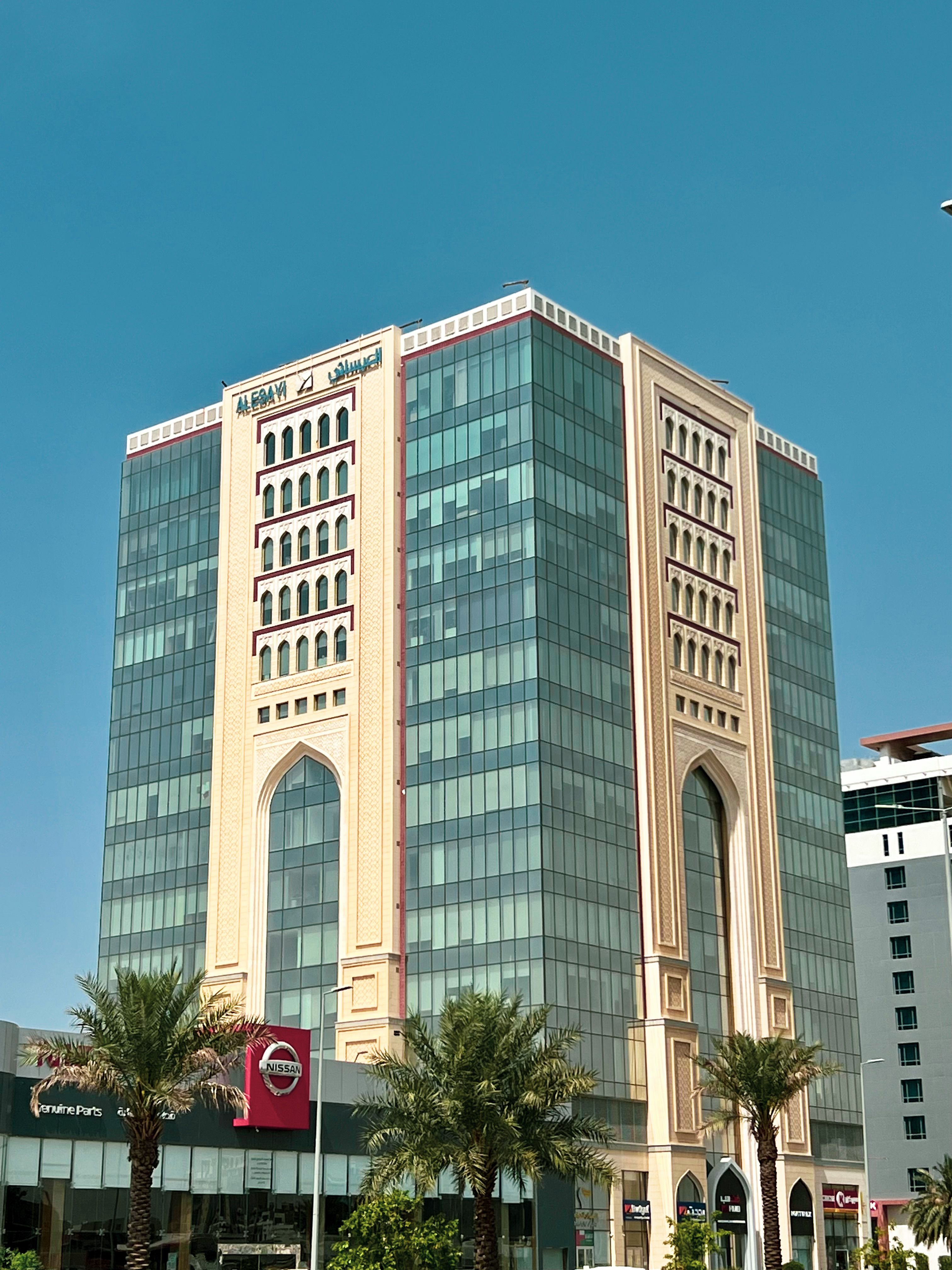 A contemporary office building with glass façade and distinctive arched entrances captured on a clear day.