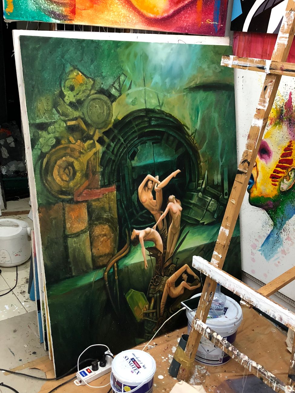 Colorful abstract surreal painting in studio with tools and easel.