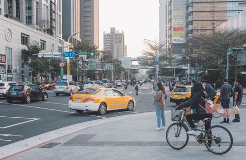 Free A bustling Taipei street scene with cyclists, taxis, and pedestrians at a city intersection. Stock Photo