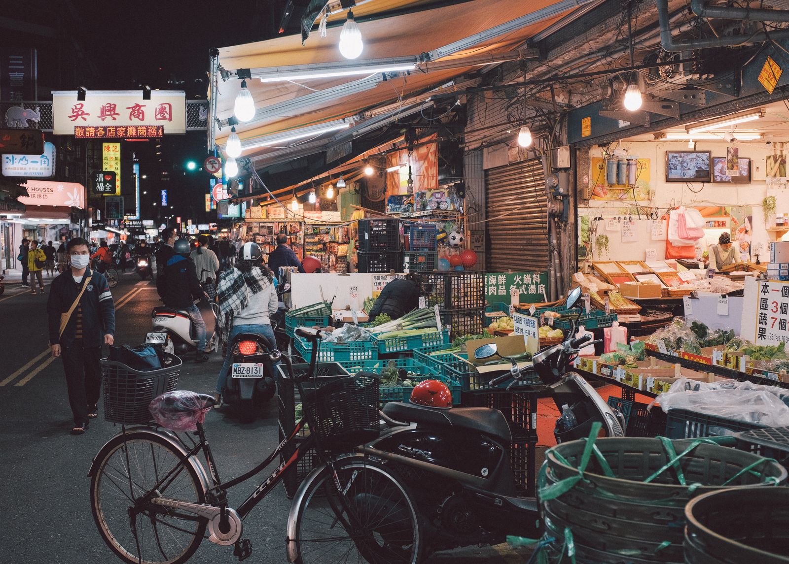 Taipei night-market street scene with vendors, pedestrians, lights, and the evening economy.