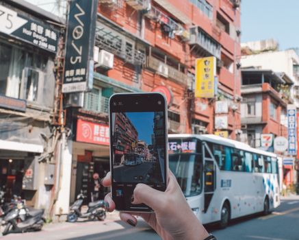 A person capturing a bustling city street with a smartphone, highlighting urban life.