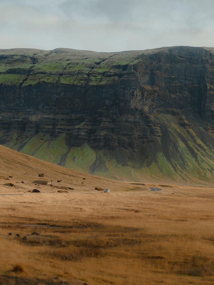 Green Rocky Mountain And Dry Yellow Field