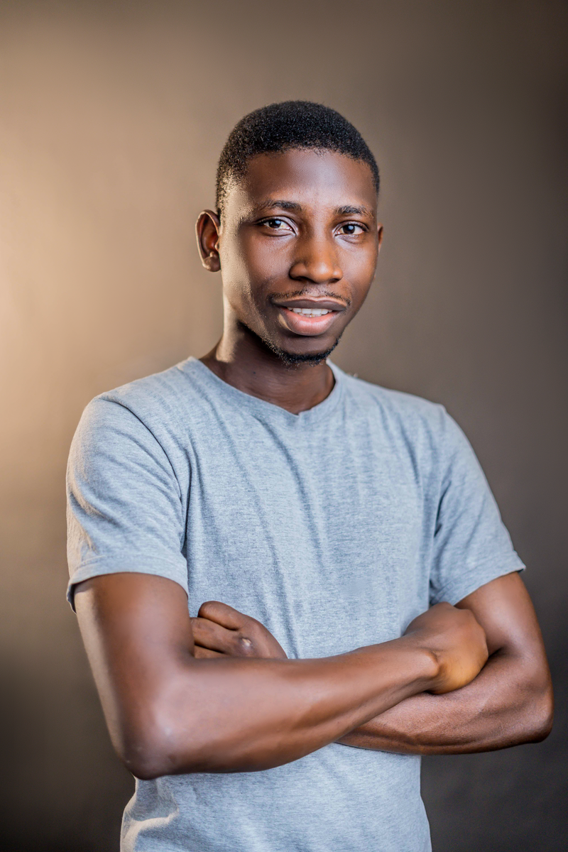 Portrait of a young man in a casual t-shirt posing confidently with crossed arms in a studio setting.