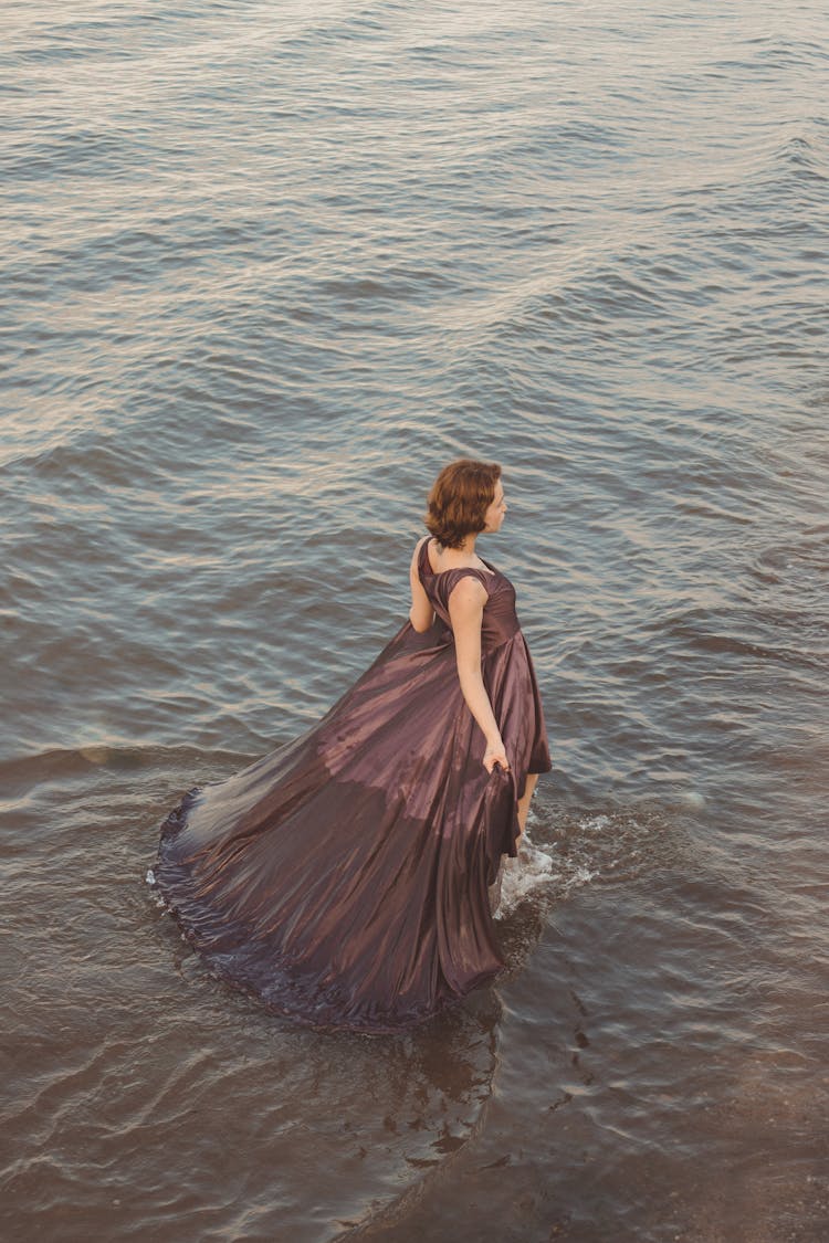 Woman In Dress Posing In Water On Seashore