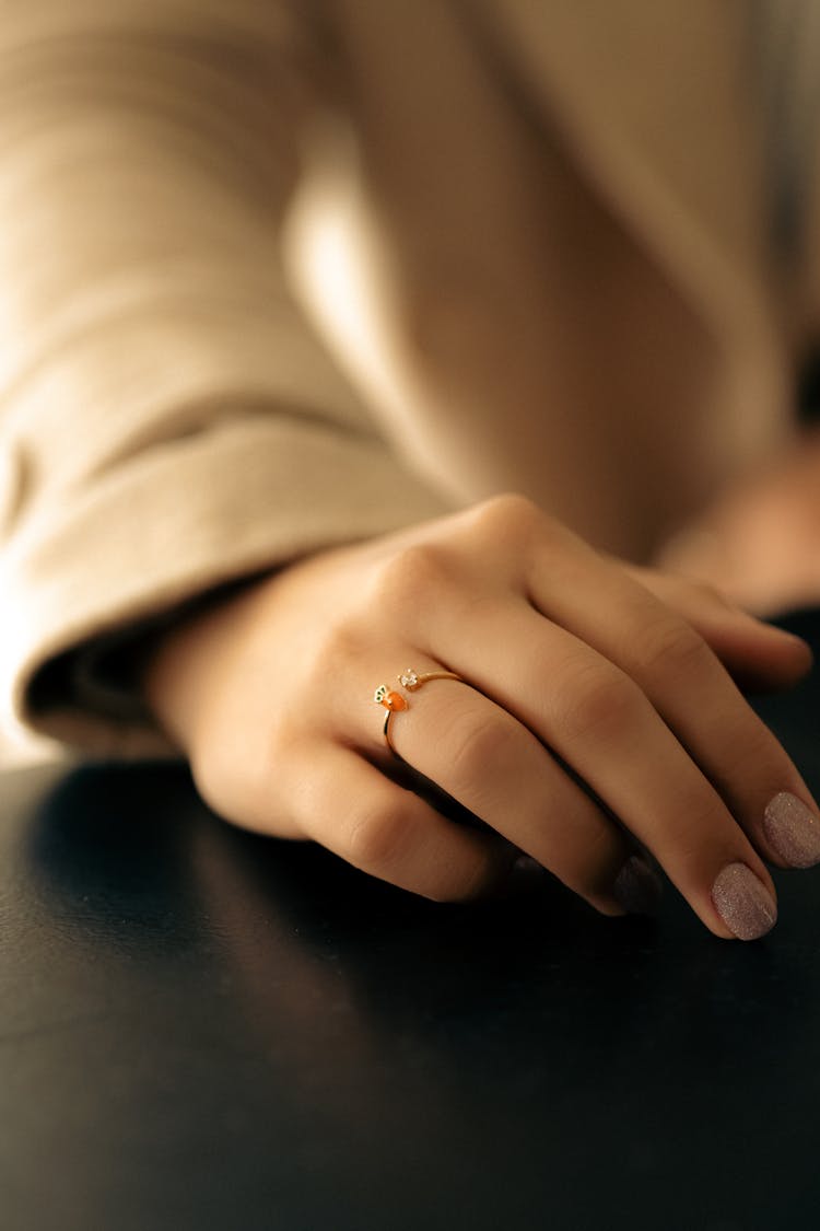 Hand With Ring Lying On A Black Table