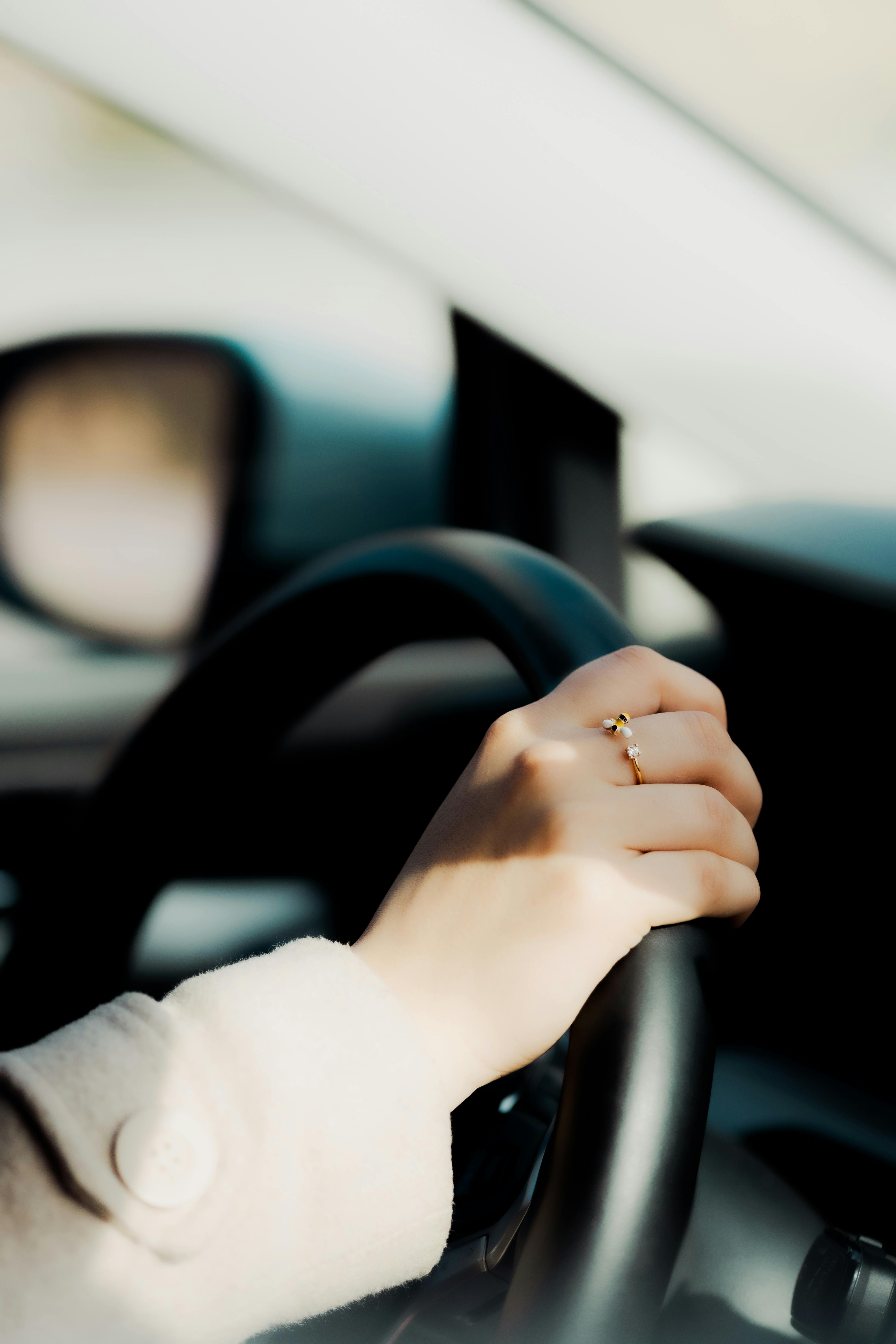 hand with a ring on a steering car wheel