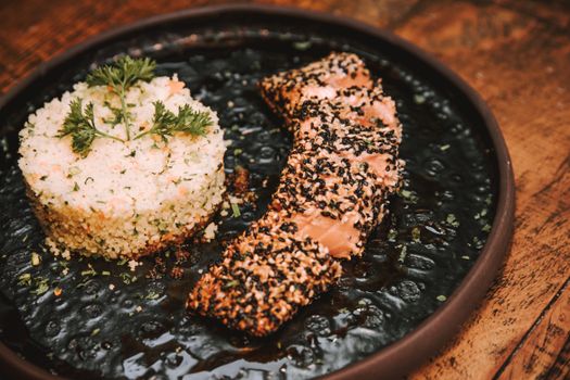 Tasty sesame-crusted salmon served with a flavorful rice medley on a rustic plate.