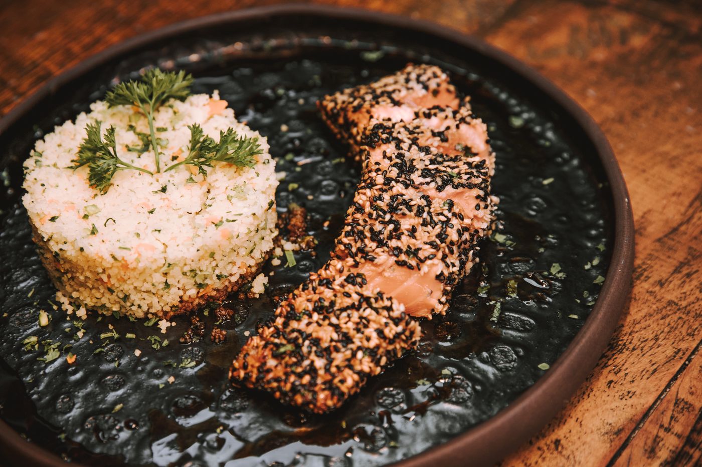 Tasty sesame-crusted salmon served with a flavorful rice medley on a rustic plate.