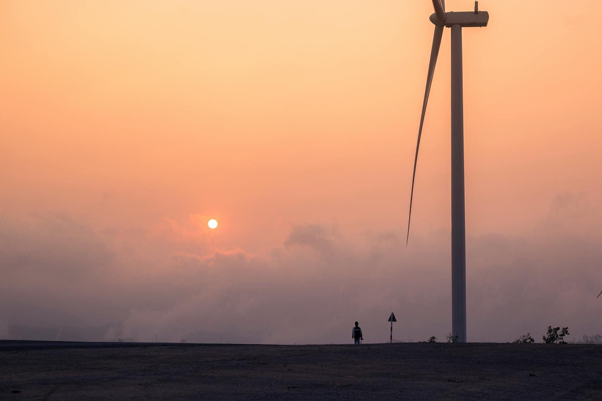 A wind turbine towering against a colorful sunset sky, symbolizing renewable energy in rural settings.