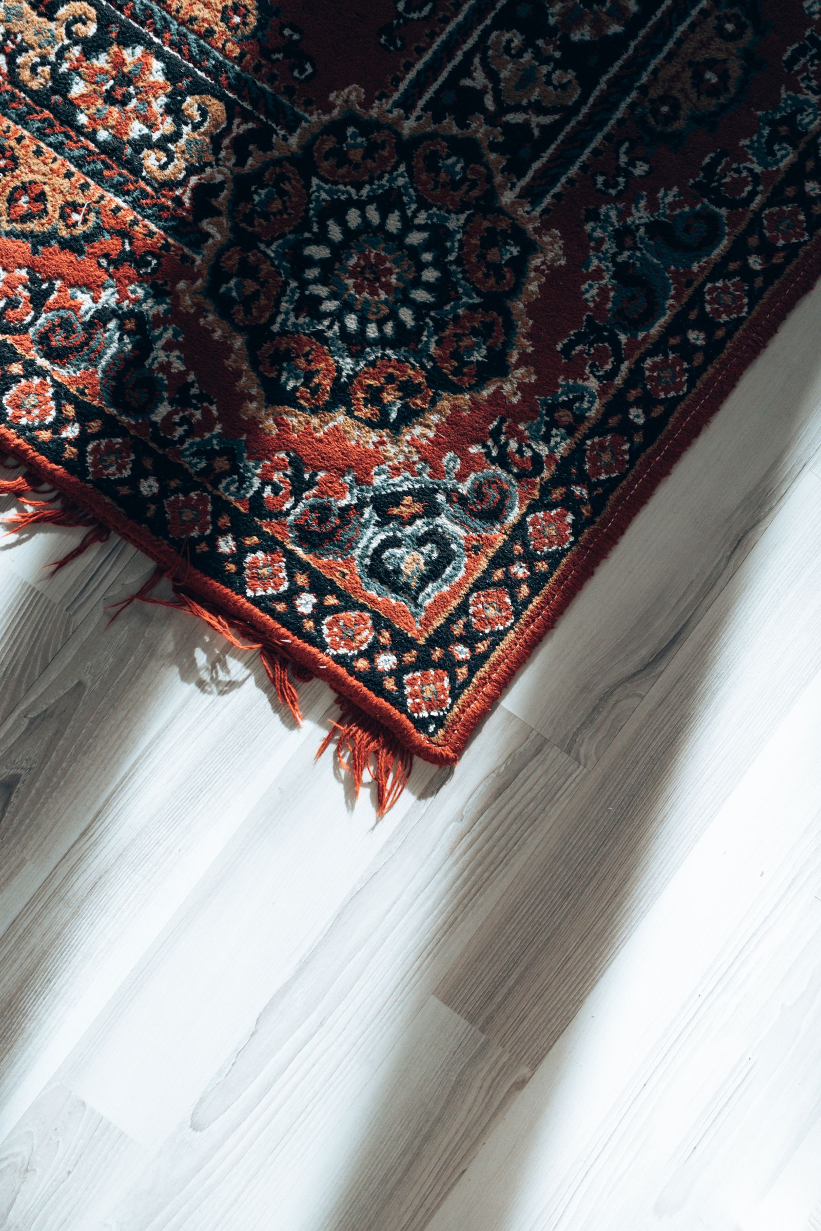 The fringed corner of an oriental rug on a wood floor