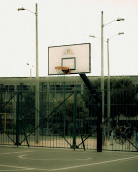 Basketball hoop and urban court scene captured in Bogotá, Colombia with streetlights and urban fencing.