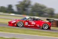 一辆红色赛车在充满活力的阳光下飞驰在赛道上