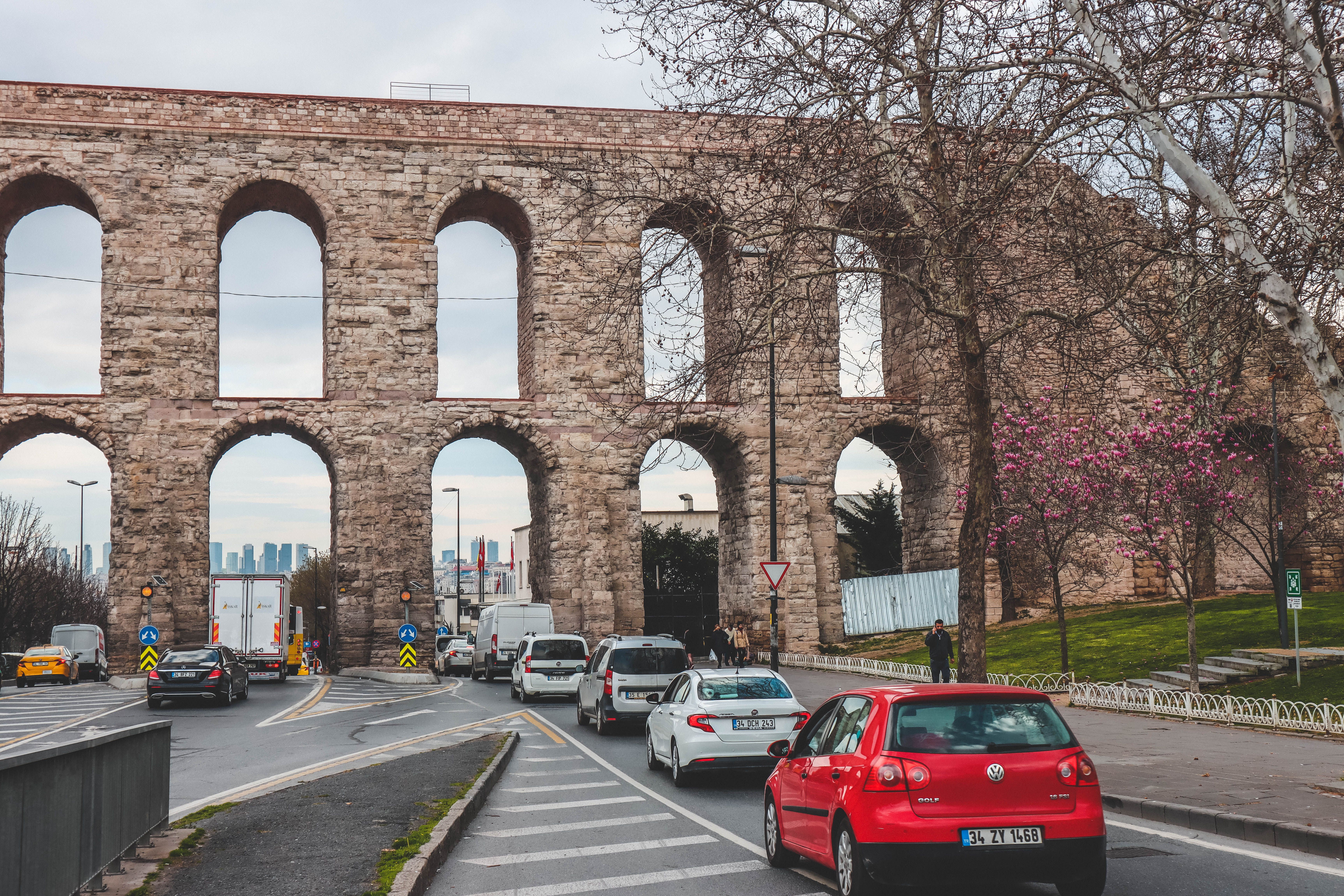 Day-trippers crowding the steps beside the aqueduct at midday, with an empty street beyond