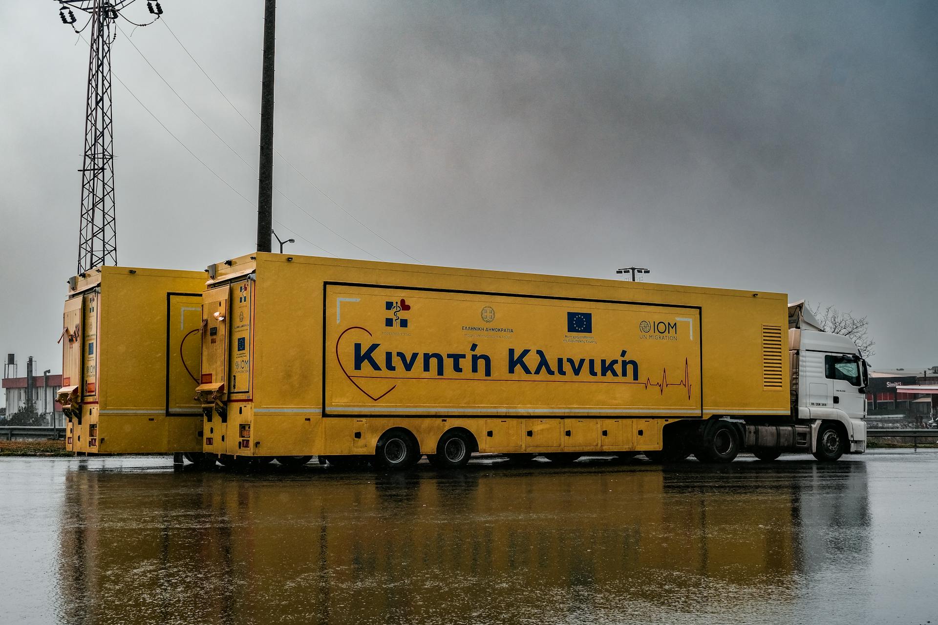 Yellow mobile clinic truck parked outdoors in Tekirdağ on a rainy day, showcasing logistics.