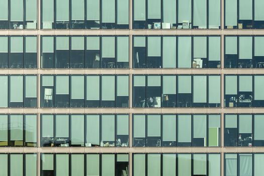 Aerial view of a modern office building facade featuring sunlit windows and minimalistic design.