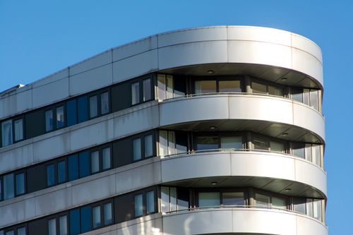 Free A modern building with curved design and large windows under a clear blue sky. Stock Photo