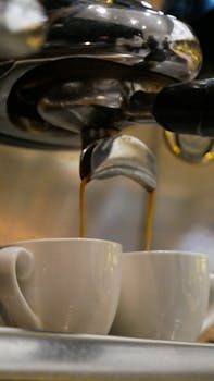 Close-up of double espresso being poured into cups from a coffee machine.