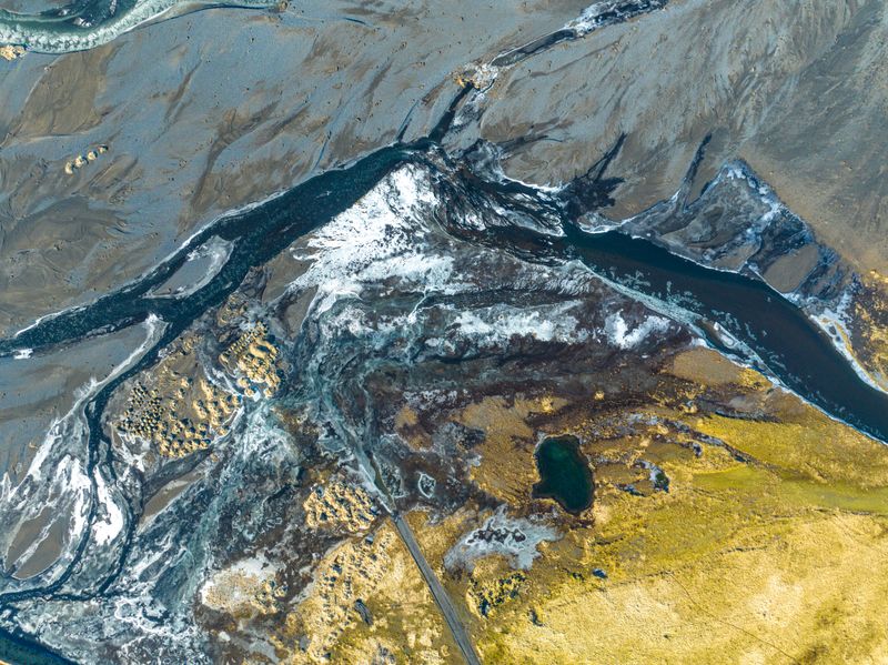 Aerial view of river channels branching and reconverging across mossy terrain