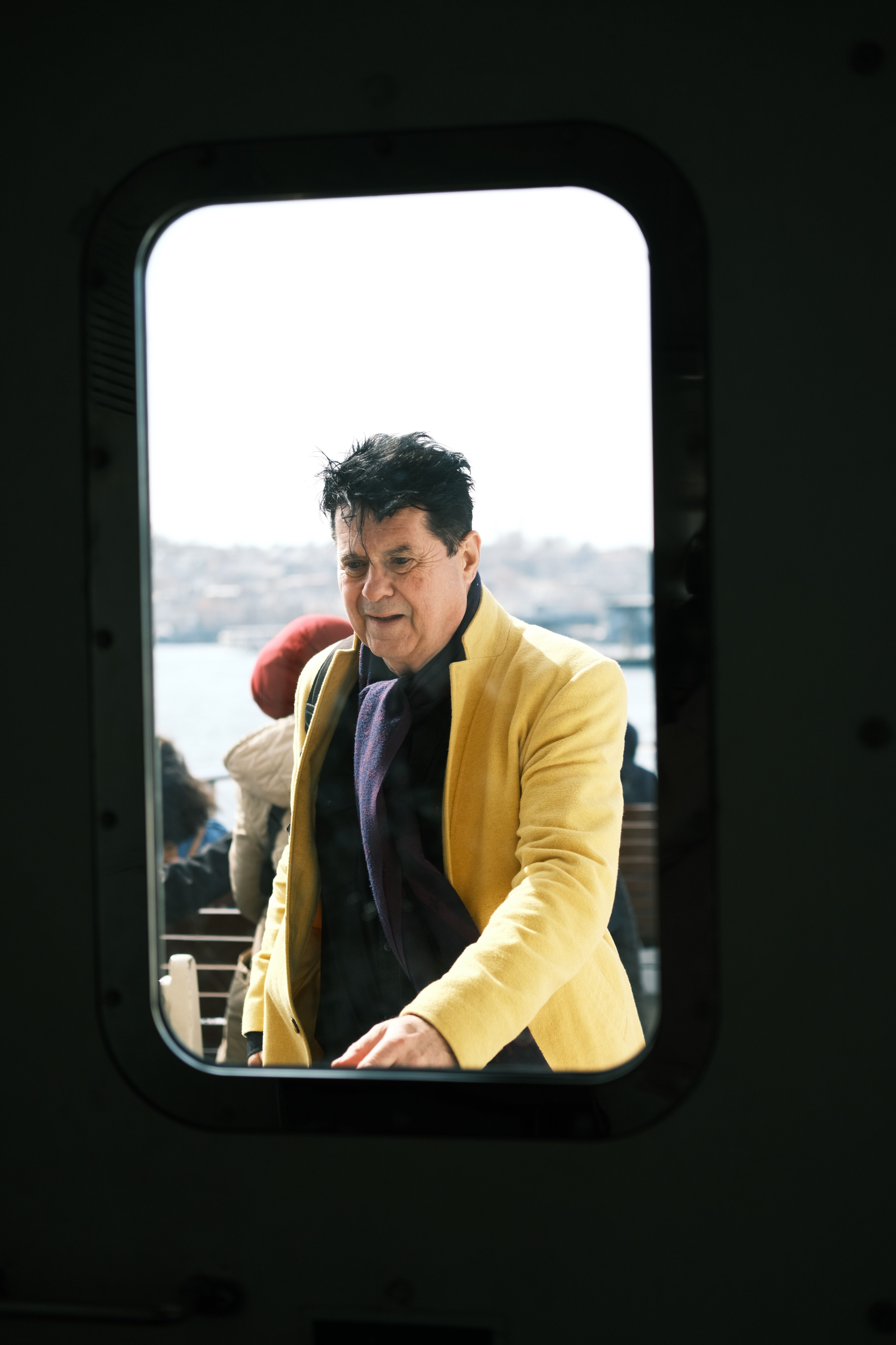 A man in a yellow jacket seen through a window outdoors during daytime.
