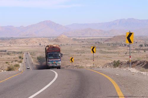 Free Colorful truck navigating a winding road in the arid mountains of Khuzdar, Pakistan. Stock Photo