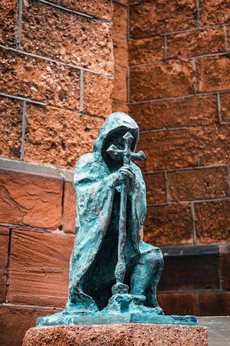 Bronze Sculpture Of A Kneeling Monk With A Cross