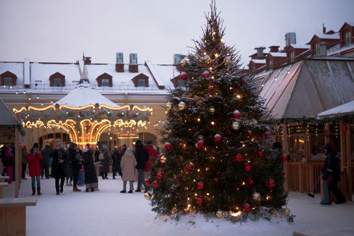 Free A lively Christmas market with a decorated tree and carousel, creating a festive winter atmosphere. Stock Photo