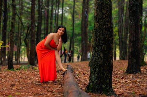 Portrait of a Long-Haired Brunette Wearing a Red Dress Posing in a Forest