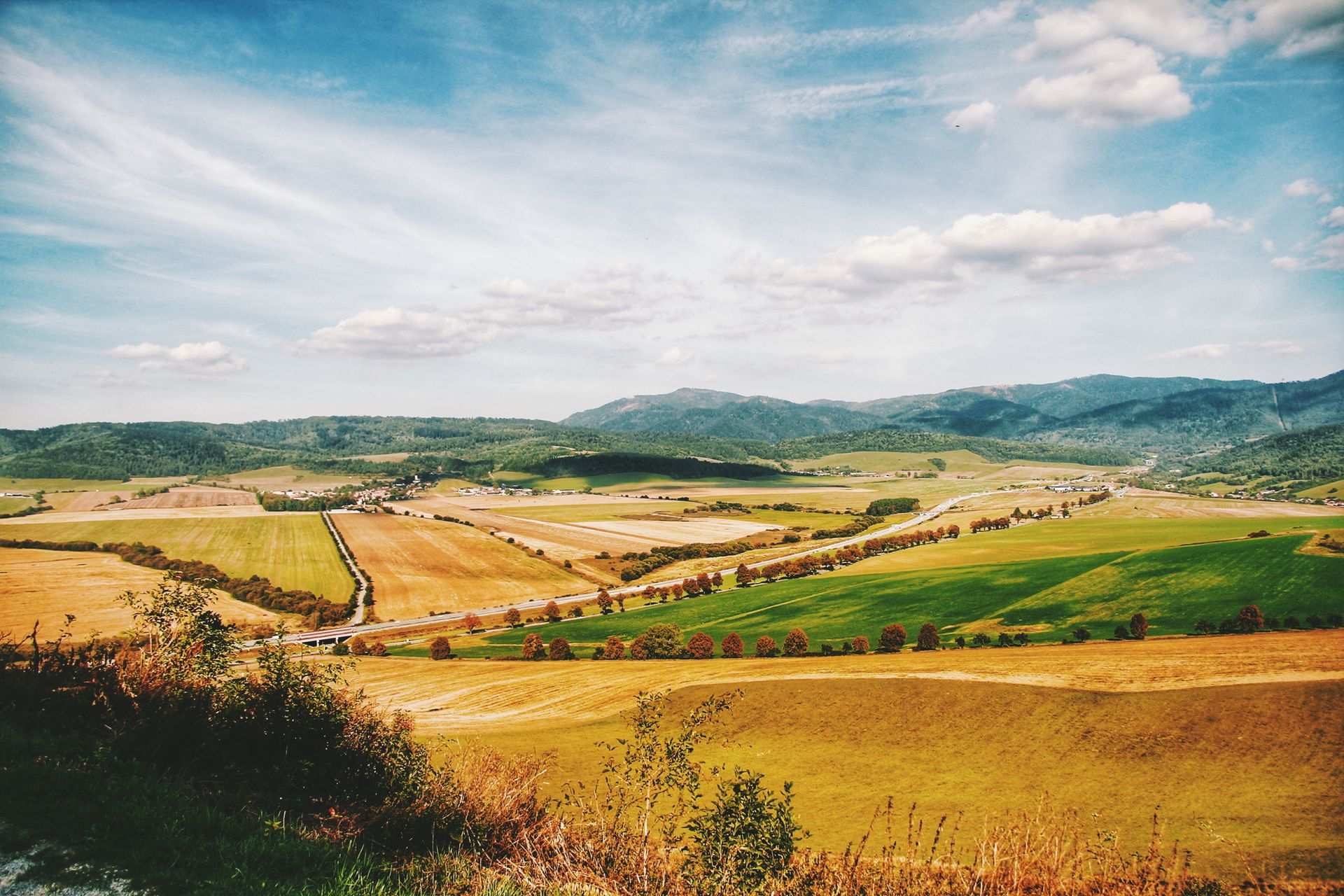 Scenic view of vibrant summer fields and hills under a clear blue sky.