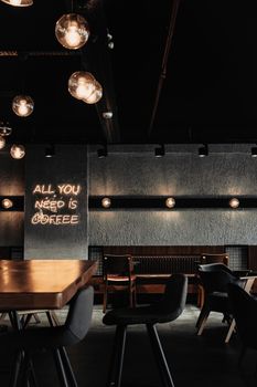 Cozy café interior with a neon light slogan sign emphasizing coffee need.