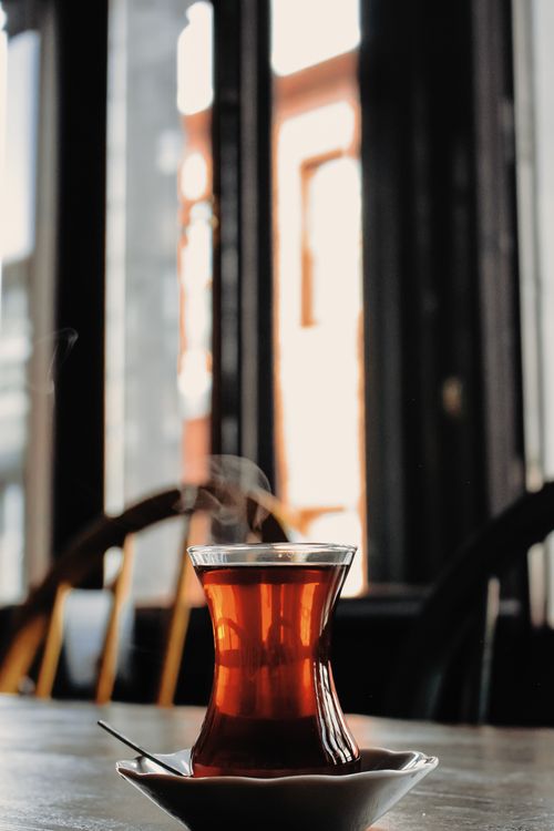 Free A steaming glass of Turkish tea photographed indoors on a wooden table with a blurred background. Stock Photo