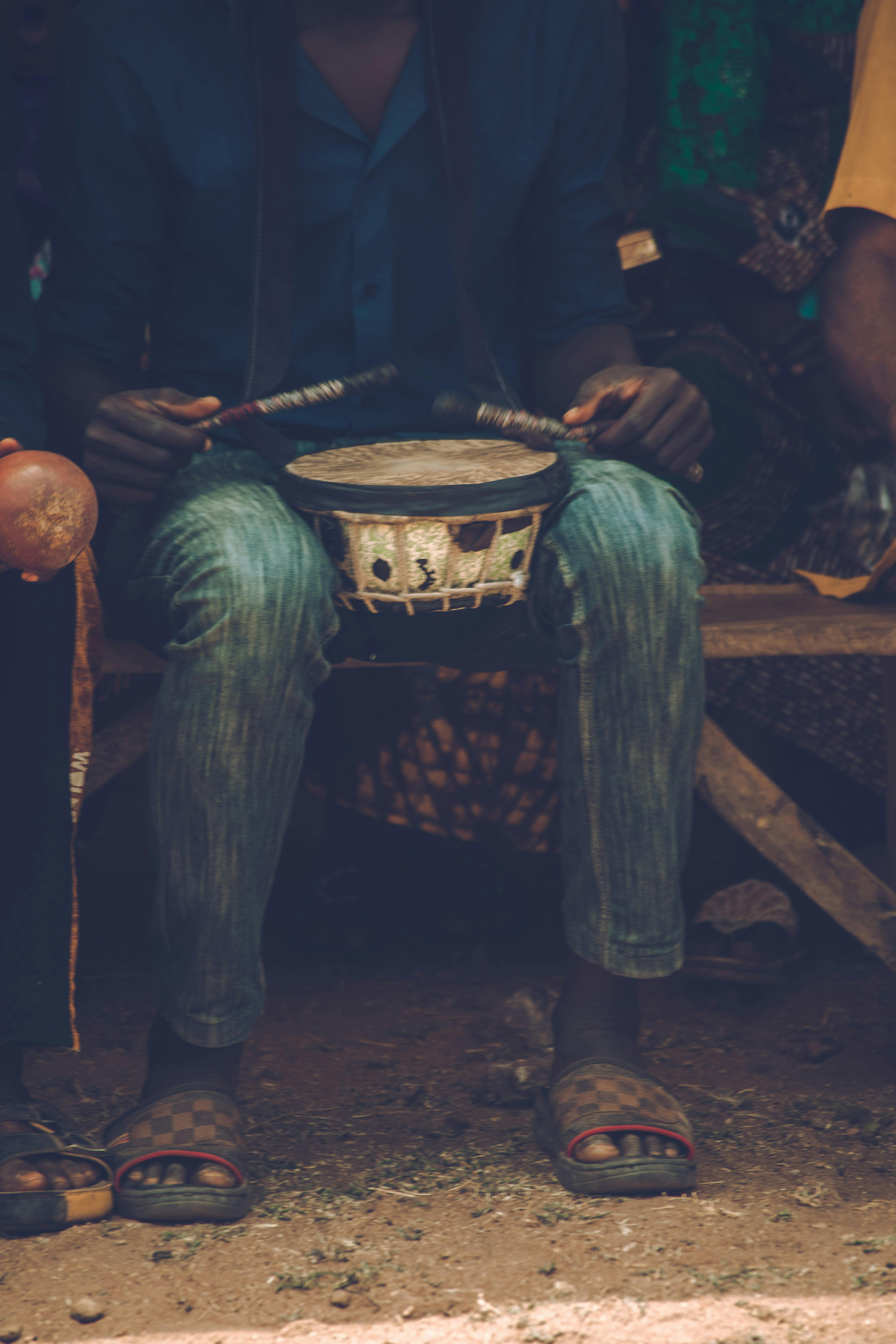 Playing a Small Drum Held Between the Knees · Free Stock Photo