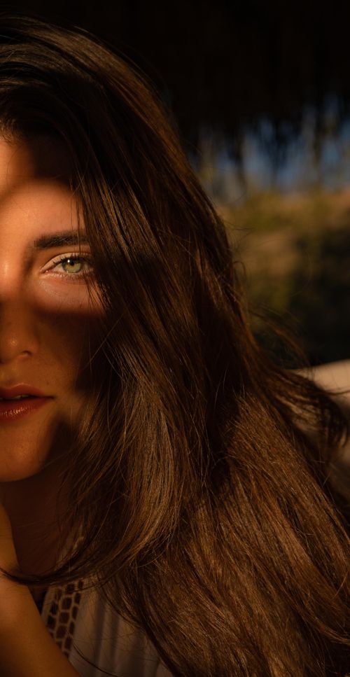 Free A captivating portrait of a woman with long brown hair in partial shadow, casting a mysterious and serene vibe. Stock Photo