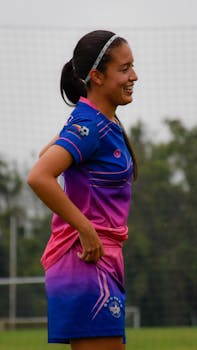 Joyful teenage girl in colorful sportswear playing soccer outdoors.