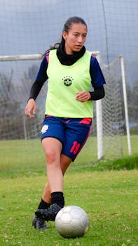 A young woman playing soccer on a grassy field, showcasing her athletic skills.