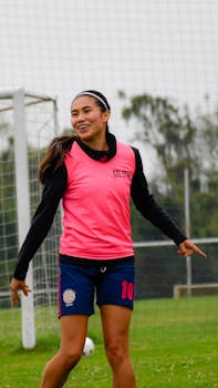 Teen girl playing soccer outdoors in sportswear, smiling confidently on the field.