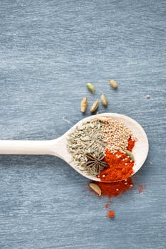 木勺中盛放着八角茴香和辣椒粉等香料，置于带有纹理的蓝色表面，呈现顶视图