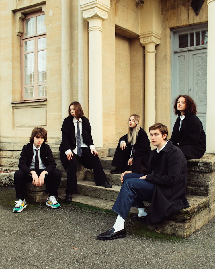 A Group Of Schoolgirls And Schoolboys In Uniforms Sitting On Steps