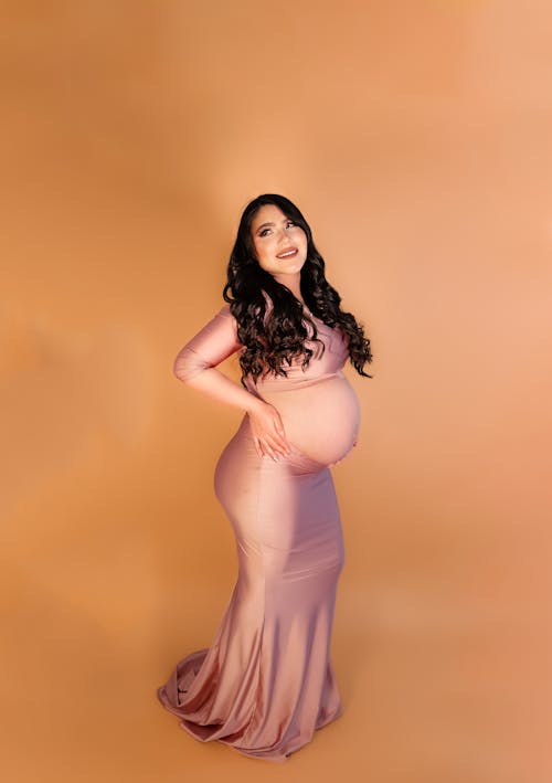 Pregnant Woman in Pink Gown Cradling her Belly