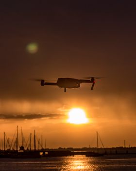 A drone flies over Melbourne's bay at sunset, capturing a stunning silhouette against the golden hour sky.