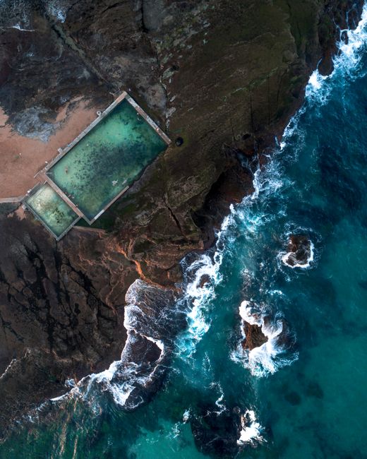 Stunning aerial shot of Mona Vale rock pool and crashing ocean waves in New South Wales, Australia.