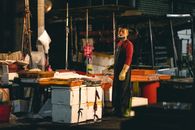 Street vendor at night stall wearing apron and gloves, ready for business.