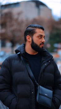 Stylish man in black puffer jacket on city street during winter.