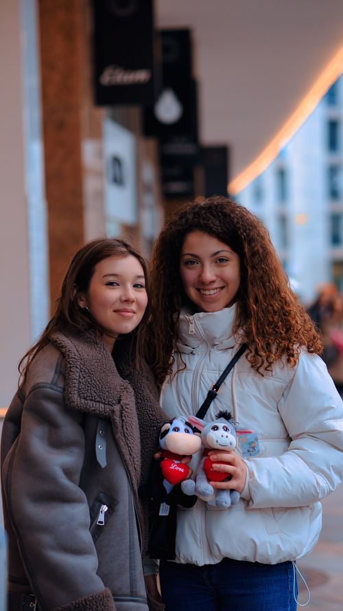 Free Two young women in cozy jackets pose outdoors holding plush toys, radiating happiness. Stock Photo