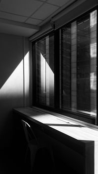 A minimalist interior showing shadows and reflections on a windowsill.
