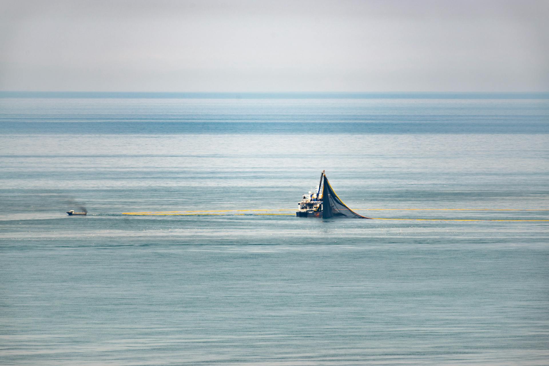 A fishing trawler navigates the calm sea, capturing the serene oceanic landscape.