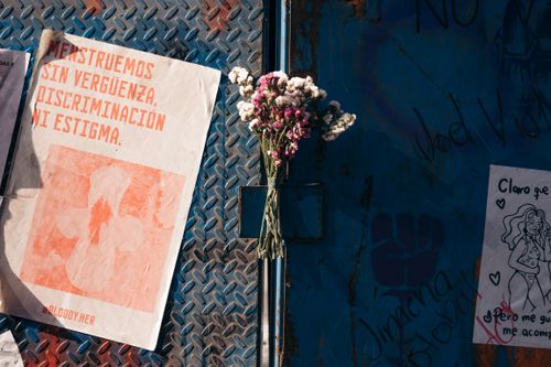 Free Bouquet and feminist posters on an urban wall signifying empowerment and protest. Stock Photo