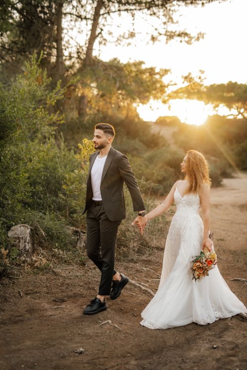Free Bride and groom walking hand in hand during sunset in Antalya, Türkiye. Stock Photo