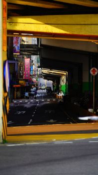 Vibrant city street scene captured beneath a highway overpass with colorful signs.