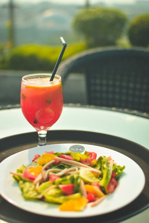 Free Drink Beside Salad on Black Tray Stock Photo
