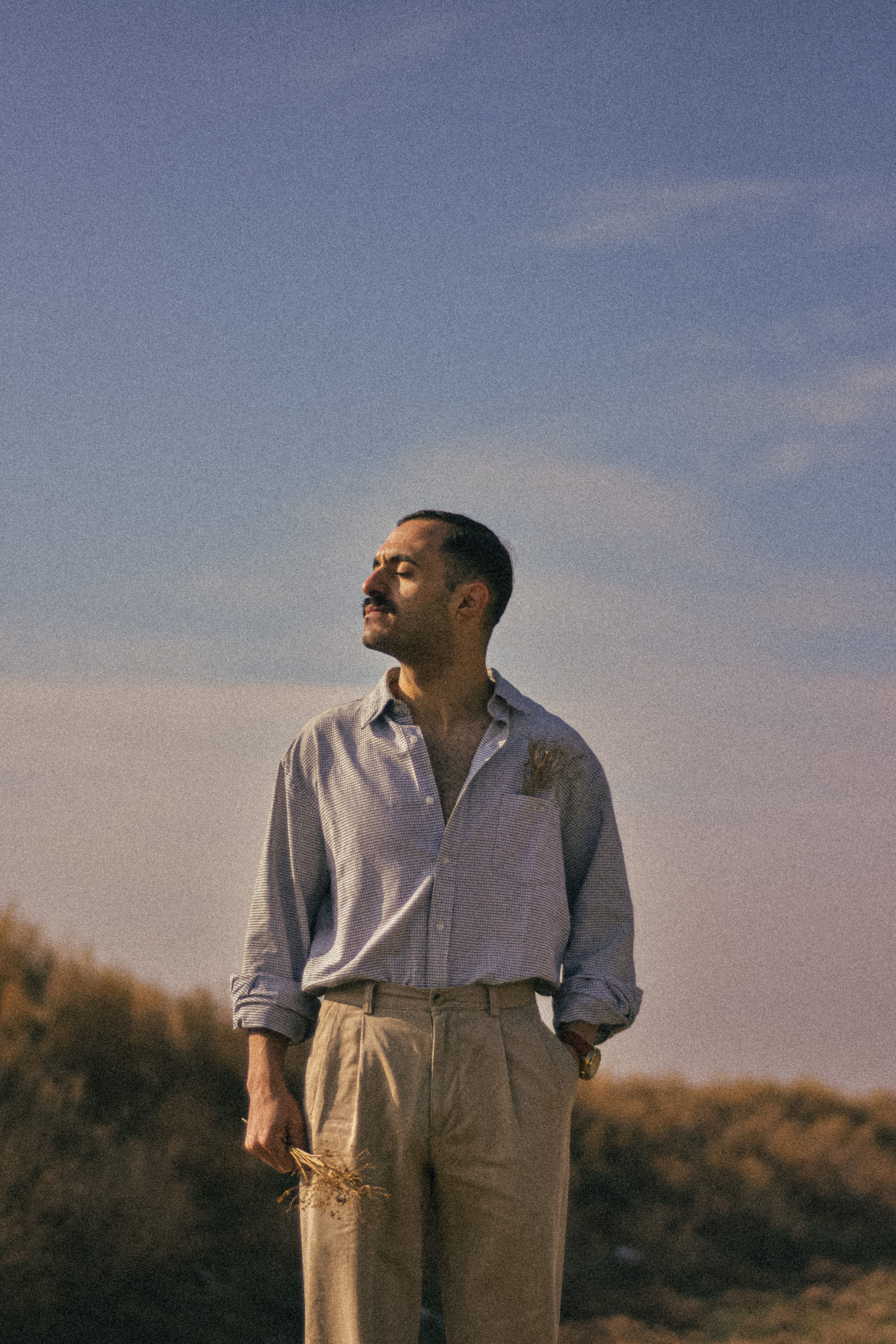 A man in beige trousers and blue shirt enjoying the outdoors under a clear sky.